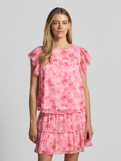 Frauenmodel trägt Regular Fit Top aus Chiffon Modell 'SMILLA' von Vero Moda mit Allover-Muster in Rosa und kurzen Schmetterlingsärmeln, Ganzkörperansicht von vorne.