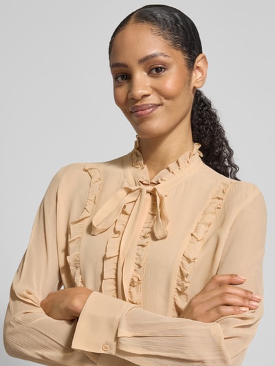 Frauenmodel trägt Regular Fit Bluse aus Seide mit Rüschen von HERZENS in Beige, feine Struktur, Schluppe, Knopfleiste, Nahaufnahme Oberkörper.