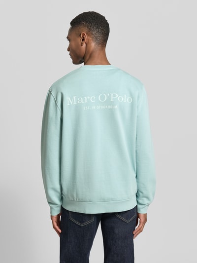 Männermodel trägt Regular Fit Sweatjacke aus reiner Baumwolle von Marc O'Polo in Hellblau mit Label Print, gerippten Abschlüssen, Ganzkörperansicht Rückansicht.