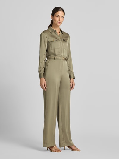 Frauenmodel trägt Jumpsuit mit Taillengürtel von MICHAEL Michael Kors in Khaki, Satin, Crinkle-Optik, lockere Passform, Ganzkörperansicht von vorne.