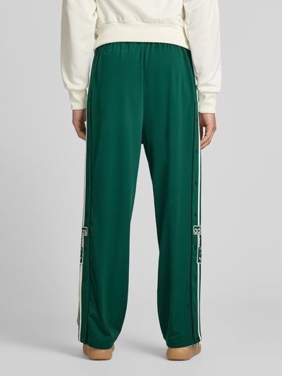 Männermodel trägt Sweatpants mit elastischem Bund Modell "ADIBREAK" von adidas Originals in Grün mit Label-Stitching und Eingrifftaschen, Lockerer-Schnitt, Innenbeinlänge 74 cm bei Größe M, Ganzkörperansicht Rückansicht.