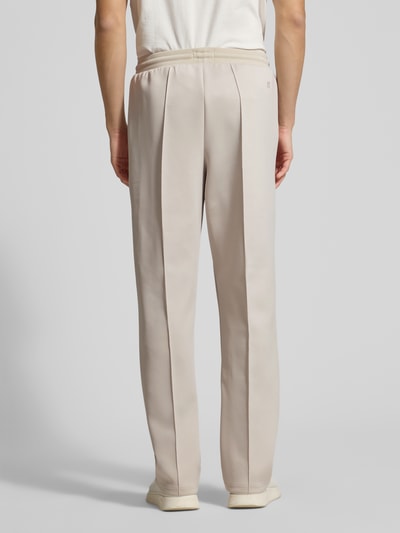 Męski model nosi Track Pants mit Eingrifftaschen Modell 'Ballier' von Les Deux w beżowym kolorze, prosty krój, elastyczny pas, widok całopostaciowy tył.
