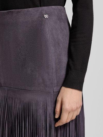 Vrouwenmodel draagt Lederrock mit Fransen und rückseitigem Reißverschluss van Marc Cain, echt leer, franjes, recht, close-up taille, nahaufnahme bovenlichaam.
