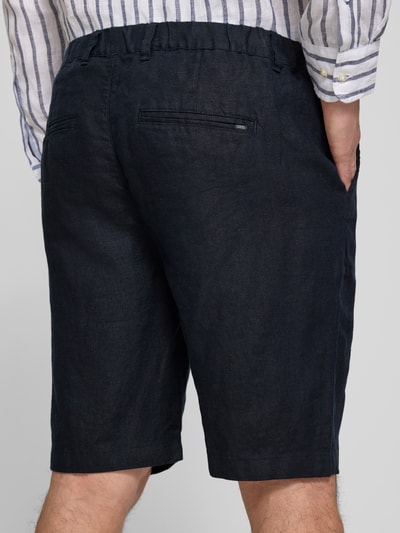 Mężczyznamodel nosi Leinen Shorts mit Eingrifftaschen Modell 'PANDRUP' od Casual Friday, czarne, proste nogawki, len, krój straight fit, kieszenie boczne, tylne kieszenie listewkowe, szerokość w rozmiarze M: 44 cm, długość nogawki od wewnątrz w rozmiarze M: 23 cm, widok całej sylwetki od tyłu.