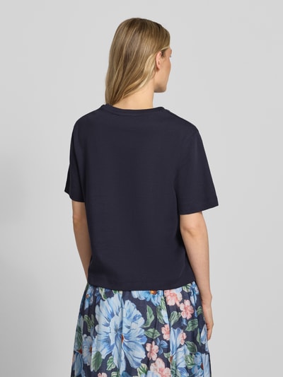 Modelka kobieca nosi T-Shirt mit Logo-Stitching Modell 'SVEHA' marki Oui z czystej bawełny, prosty krój, okrągły dekolt, długość tyłu w rozmiarze 36: 55 cm, ciemnogranatowy, gładka faktura, widok całej sylwetki z tyłu.