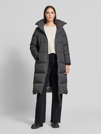 Frauenmodel trägt Regular Fit Daunenmantel mit abnehmbaren Rucksackriemen von Marc O'Polo in Dunkelgrau, glatte Oberfläche, Ganzkörperansicht von vorne. Damen Daunenmantel von Marc O'Polo