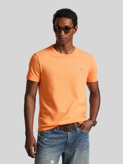 Männermodel trägt Regular Fit T-Shirt aus reiner Baumwolle von Polo Ralph Lauren in Unifarbe Orange mit Logo-Stitching, Ganzkörperansicht von vorne.