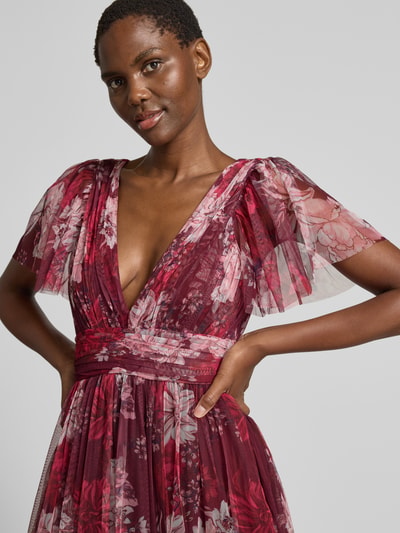 Frauenmodel trägt Cocktailkleid mit tiefem V-Ausschnitt von LACE & BEADS, florales Mesh, A-Linie, Midikleid, Stufen-Look, Nahaufnahme Oberkörper.