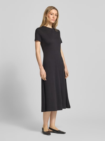 Frauenmodel trägt Midikleid aus reiner Baumwolle von Tommy Hilfiger in Uni-Schwarz, Regular Fit, Kurzarm, Rundhals, Logo-Stitching, Ganzkörperansicht von vorne.
