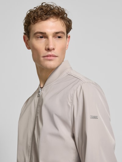 Männermodel trägt Regular Fit Jacke mit Stehkragen Modell 'Rapid' von CINQUE in beige, glatte Textur, Nahaufnahme Oberkörper, tweewegrits, elastische boorden, ruglengte 69 cm, schouderbreedte 46 cm, borstwijdte 55 cm, mouwlengte 70 cm.