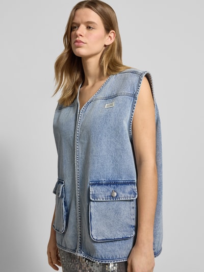 Frauenmodel trägt Jeansweste mit Label-Patch von Karo Kauer in Blau, Reine Baumwolle, Loose-Fit, V-Ausschnitt, Reißverschluss, Pattentaschen, Ganzkörperansicht von vorne. Rückenlänge 71 cm, Schulterbreite 48 cm, Brustweite 65 cm in Größe S.
