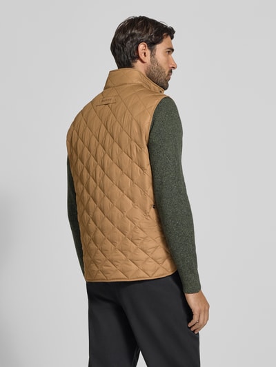 Männermodel trägt braune, gesteppte Slim Fit Weste mit Logo-Stitching Modell 'NEW LOWERDALE' von Barbour, Herren Weste, Ganzkörperansicht Rückansicht.