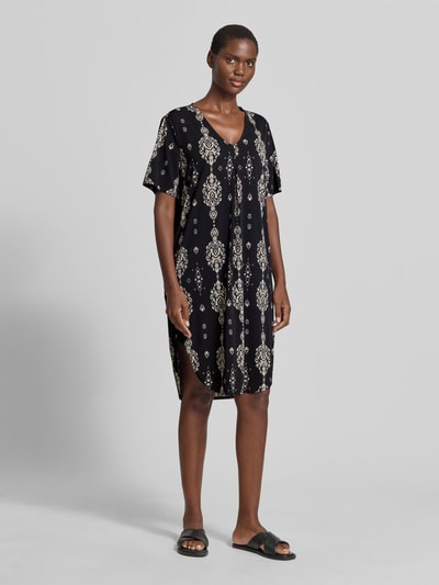 Frauenmodel trägt Knielanges Kleid mit V-Ausschnitt Modell 'Floy' von FREE/QUENT in Schwarz mit beigem Muster, gerader Schnitt, Material-Mix mit Stretch-Anteil, Ganzkörperansicht von vorne.