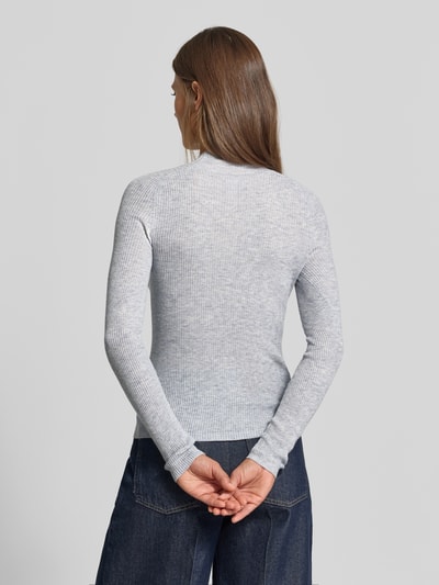 Frauenmodel trägt Strickpullover mit Woll-Anteil von MYON, eng anliegend, Stehkragen, Ripp-Optik, Produktdetails sichtbar, Ganzkörperansicht Rückansicht.