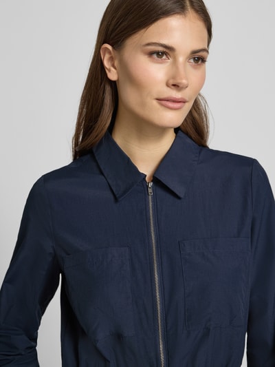 Kobiece model prezentuje sukienkę koszulową Hemdblusenkleid mit Reißverschluss Modell 'NETTI' od Soyaconcept z mieszanki bawełny, linia a, sukienka midi, zamek błyskawiczny, elastyczna tasiemka w talii, długość tyłu w rozmiarze s: 121 cm, szerokość w rozmiarze s: 42 cm, długość rękawów w rozmiarze s: 60 cm, granatowa, prosta faktura, zbliżenie na górną część tułowia.
