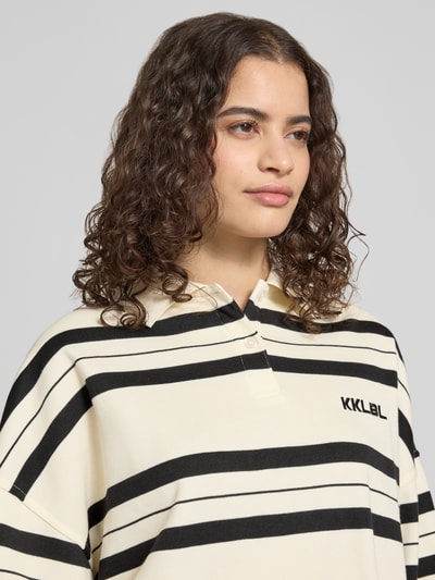 Frauenmodel trägt Oversized Polo-Langarmshirt mit Streifenmuster von Karo Kauer, mieszanka bawełny, wyhaftowane logo, listwa guzikowa, wzór w paski, styl oversized, długość tyłu w rozmiarze S: 71 cm, Nahaufnahme Oberkörper
