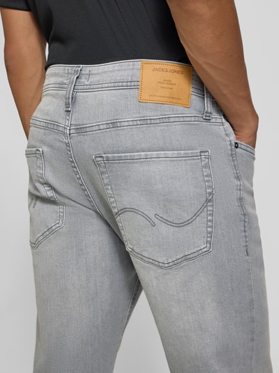 Männermodel trägt Straight Fit Jeans mit Stretch-Anteil Modell 'MIKE' von JACK & JONES, Mieszanka bawełny i elastanu, 5 kieszeni, szare kolory, Szerokość w rozmiarze 32/32: 44 cm, Długość wewnętrzna nogawki: 78 cm, zapięcie na guzik i zamek błyskawiczny, Ganzkörperansicht Rückansicht