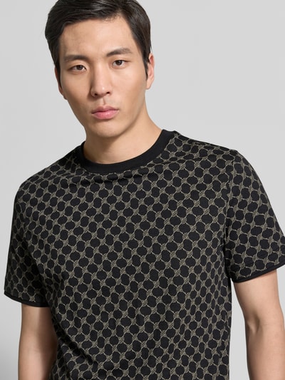 Männermodel trägt T-Shirt mit Logo-Muster und Rundhalsausschnitt von JOOP! Collection im Baumwoll-Lyocell-Mix, Regular-Fit, Nahaufnahme Oberkörper.