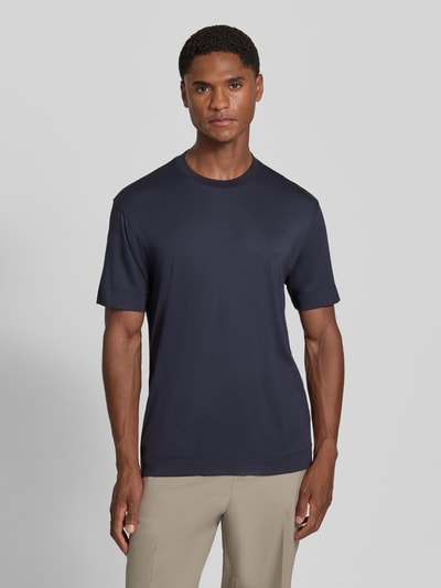Männermodel trägt T-Shirt mit Logo-Stitching von Emporio Armani in Dunkelblau, glatte Textur, Rundhalsausschnitt, Ganzkörperansicht von vorne.