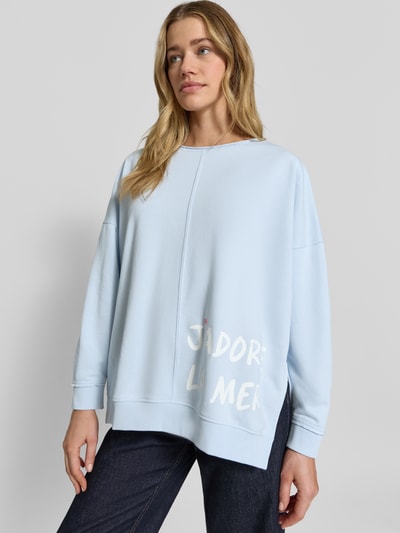 Frauenmodel trägt Oversized Sweatshirt mit Statement-Print und Rollsaum von Smith and Soul in Hellblau aus Baumwoll-Mix mit Modal-Anteil, Rundhalsausschnitt, überschnittenen Schultern und Rollsaum, Statement-Print in Weiß, Struktur glatt, Ganzkörperansicht von vorne.