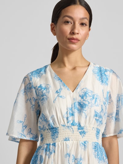 Frauenmodel trägt Damen Midikleid aus Lyocell-Mix Modell 'Evangelia' von MSCH Copenhagen mit Allover-Look, V-Ausschnitt, Nahaufnahme Oberkörper. Rückenlänge 131 cm, Brustweite 41 cm, Ärmellänge 31 cm. Helle Farben, blaue Blumen, strukturierte Taillenpartie.