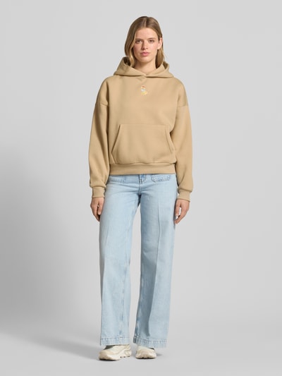 Frauenmodel trägt Hoodie mit Motiv-Stitching und Känguru-Tasche von REVIEW in Beige, Baumwoll-Mix, Regular-Fit, Ganzkörperansicht von vorne.