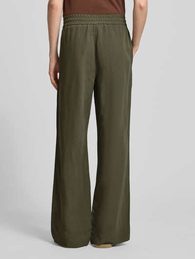 Frauenmodel trägt Leinenhose mit elastischem Bund Modell 'Roma' von STEHMANN in Olivgrün, Wide-Leg-Pants, reine Leinen, Ganzkörperansicht Rückansicht.