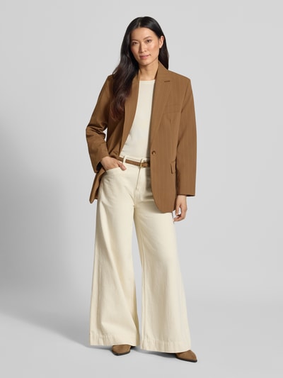 Frauenmodel trägt Relaxed Fit Blazer mit Pattentaschen Modell 'SYSTECK' von Mango in Braun, kombiniert mit heller Hose, Material-Mix mit Woll-Anteil, Reverskragen, Knopfverschluss, Ganzkörperansicht von vorne.