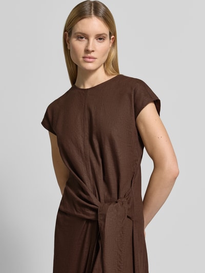 Vrouwenmodel draagt Relaxed Fit Leinenbluse mit V-Ausschnitt van Scotch & Soda in bruin, mix van linnen en viscose, met korte mouwen, relaxed fit, V-hals en overlappende schouders, ruglengte maat 36: 130 cm, borstwijdte: 52 cm, mouwlengte: 8 cm, detailopname bovenlichaam.