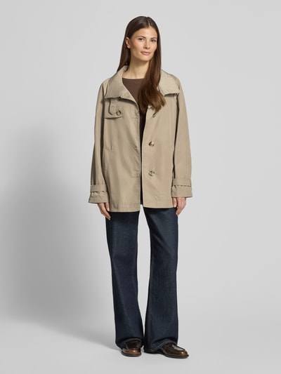 Modelka kobieca ma na sobie Trenchcoat mit Stehkragen und Ärmelriegeln od Fuchs Schmitt, relaxed fit, beżowy, długość tyłu w rozmiarze 36: 72 cm, szerokość ramion w rozmiarze 36: 40 cm, szerokość klatki piersiowej w rozmiarze 36: 54 cm, długość rękawa w rozmiarze 36: 60 cm, przód, widok całej sylwetki.