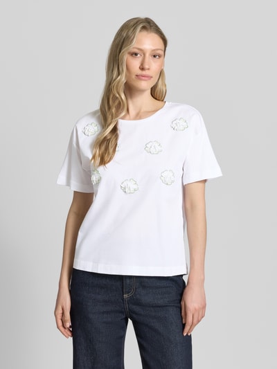 Frauenmodel trägt T-Shirt mit Stitchings und Rundhalsausschnitt von More & More, weiße Reine Baumwolle, Regular-Fit, Rückenlänge 50 cm, Ganzkörperansicht von vorne.