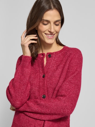 Vrouwenmodel draagt Regular Fit Strickjacke aus Woll-Mix mit Alpaka-Anteil Modell 'LULU' van Selected Femme, rood melange, knoopsluiting, ronde hals, lange raglanmouwen, gebreide textuur. Nahaufnahme bovenlichaam.
