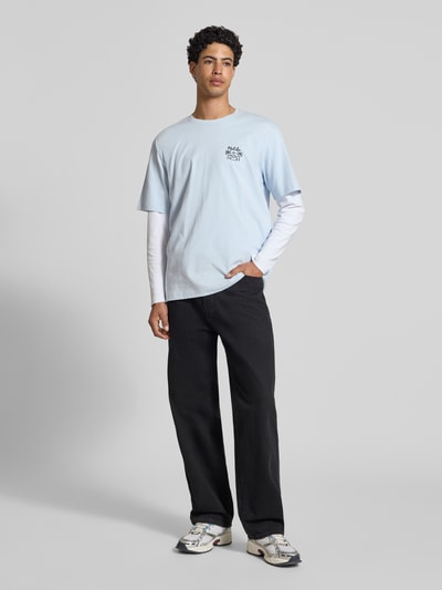 Männermodel trägt Relaxed Fit T-Shirt aus reiner Baumwolle Modell 'MILO' von Only & Sons in Hellblau mit Print, Ganzkörperansicht von vorne