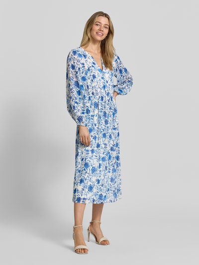 Frauenmodel trägt Midikleid aus reiner Viskose mit floralem Allover-Print von ROBE LÉGÈRE, Tailliert, Tunika-Ausschnitt, Langärmelig, Knopfleiste, Rückenlänge 123 cm, Brustweite 49 cm, Ärmellänge 60 cm, Ganzkörperansicht von vorne.