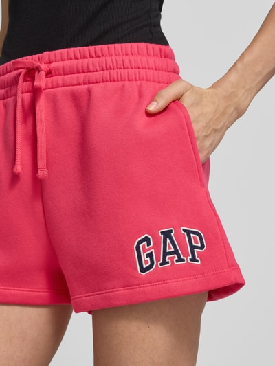 Frauenmodel trägt Sweatshorts mit Logo und elastischem Bund von GAP in Pink, Baumwoll-Mix, Regular-Fit, Logo vorne, Detailaufnahme Oberkörper.