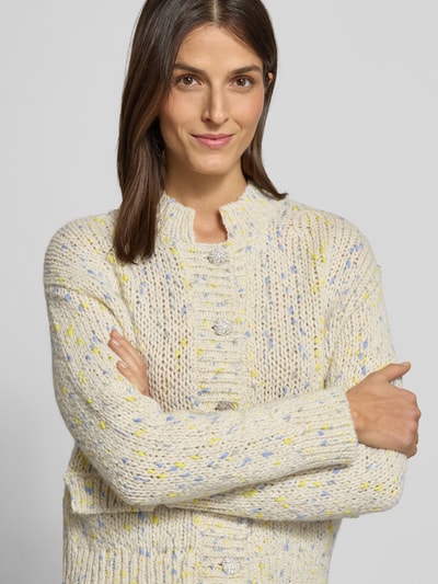 Frauenmodel trägt Strickjacke mit Knopfleiste von Rich & Royal, cremefarben mit bunten Punkten, Schurwoll-Mix, Nahaufnahme Oberkörper.