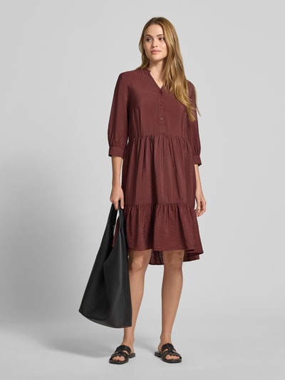 Frauenmodel trägt Relaxed Fit Midikleid aus Viskose-Mix mit Tunika-Ausschnitt, Knopfleiste und Halbarm von Christian Berg Woman, Ganzkörperansicht von vorne. Rückenlänge bei Größe 36: 106 cm, Brustweite: 45 cm, Ärmellänge: 44 cm. Schlichtes burgunderrot mit weicher, leicht strukturierter Oberfläche.