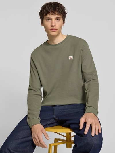 Męski model nosi Regular Fit Langarmshirt aus Baumwoll-Mix od Calvin Klein Jeans, efekt: jednolity kolor, naszywka z logo, okrągły dekolt, długi rękaw, mieszanka bawełny, widok z przodu, zbliżenie na górną część ciała