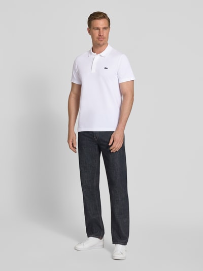 Männermodel trägt Regular Fit Poloshirt aus Baumwoll-Mix von Lacoste in Optik: Unifarben mit Logo-Patch, Polokragen, Kurzarm, Ganzkörperansicht von vorne.