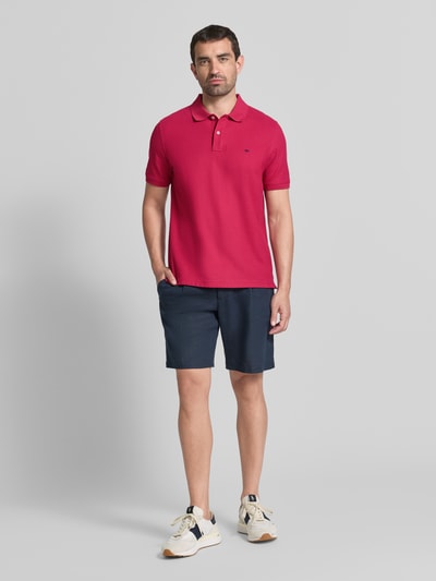 Männermodel trägt Regular Fit Poloshirt mit Label-Stitching von Fynch-Hatton in Rot, reine Baumwolle, Knopfleiste, Ganzkörperansicht von vorne.