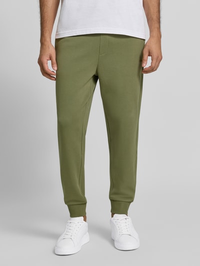 Männermodel trägt olivgrüne Regular Fit Jogginghose aus reiner Baumwolle Modell 'Dayote232' von HUGO, Nahaufnahme Unterkörper, Herren Jogginghose von HUGO.