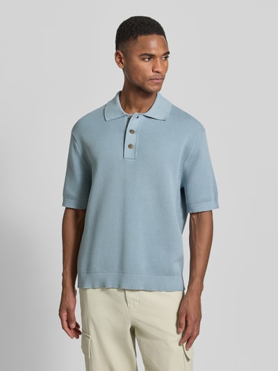 Männermodel trägt Relaxed Fit Poloshirt aus reiner Baumwolle Modell 'DANE' von SELECTED HOMME in Hellblau, Strickoptik, Ganzkörperansicht von vorne.