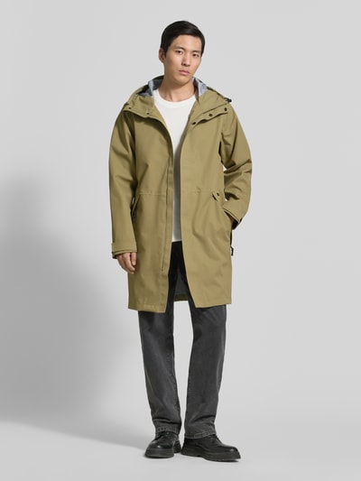 Männermodel trägt Regenjacke mit Reißverschlusstaschen Modell 'RAIN EATER' von GOFRANCK in Beige, Label-Detail, Ganzkörperansicht von vorne.