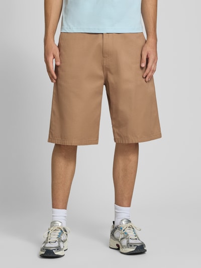 Männermodel trägt Bermudas mit Baumwoll-Anteil Modell 'Brader' von Carhartt Work In Progress in Beige, lockerer Schnitt, Ganzkörperansicht von vorne. Material-Mix, Eingriff- und Gesäßtaschen, Gürtelschlaufen, Relaxed Fit.