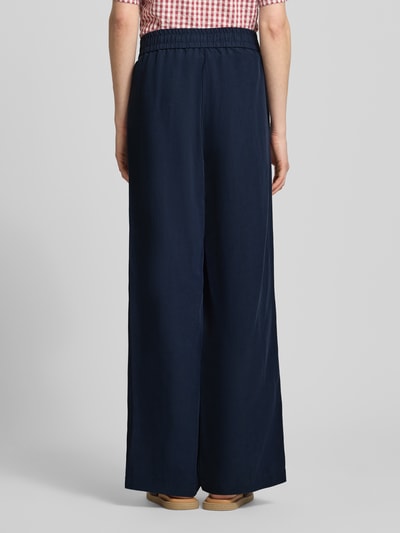 Frauenmodel trägt Leinenhose mit elastischem Bund Modell 'Roma' von STEHMANN in Dunkelblau, Wide Leg, glatte Textur, Ganzkörperansicht Rückansicht.