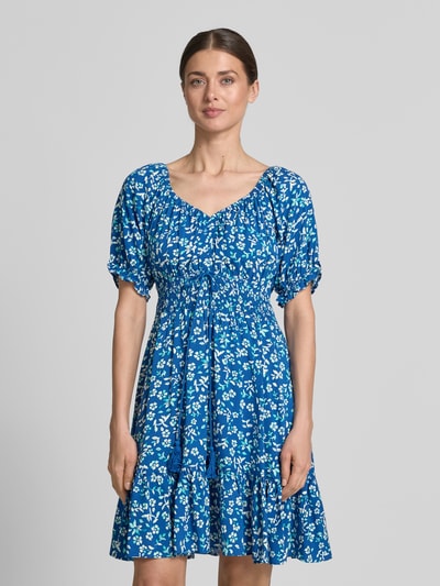 Frauenmodel trägt Minikleid aus Viskose mit Kordelzug und Quasten von Apricot in Blau mit weißen Blümchen, Taillierter Schnitt, Rundhalsausschnitt, Rüschenärmel, Smok-Detail, Rückenlänge 82 cm, Brustweite 34 cm, Ärmellänge 21 cm, Ganzkörperansicht von vorne.
