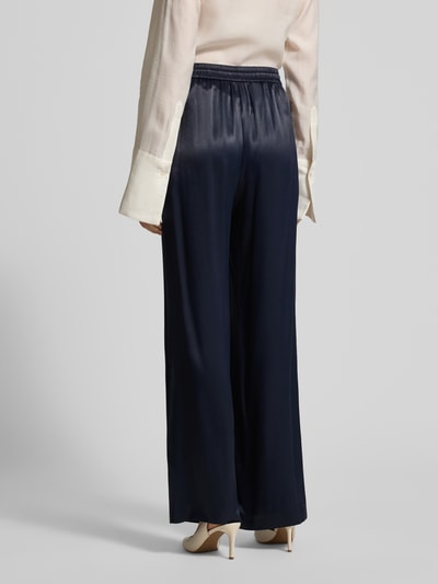 Frauenmodel trägt Wide Leg Hose aus reiner Viskose Modell 'TAVATI' von BOSS in Dunkelblau, Satin-Optik, Ganzkörperansicht Rückansicht