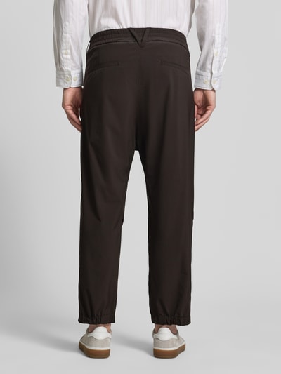 Männermodel trägt Relaxed Fit HOSE mit Bundfalten Modell 'Lirog' von Drykorn, Dunkelbraun, Elastischer-Material-Mix, Ganzkörperansicht Rückansicht, Herren, Bundweite 41 cm, Innenbeinlänge 62 cm, Eingriffstaschen, Gesäßtasche, Knopf- und Reißverschluss.