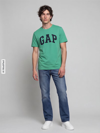 Männermodel trägt Regular Fit T-Shirt aus reiner Baumwolle Modell 'EVERYDAY SOFT' von GAP in Grün mit Logo-Print, Ganzkörperansicht von vorne, KI-modifiziertes Bild. Rückenlänge bei Größe M: 67 cm, gerippter Rundhalsausschnitt.