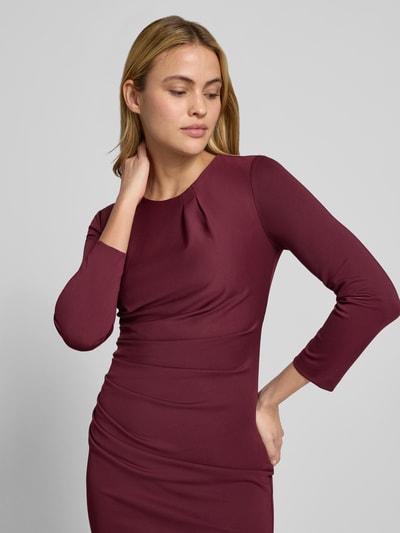Frauenmodel trägt Cocktailkleid mit Raffungen von Rinascimento in bordeaux, taillierter Material-Mix mit Stretch, Nahaufnahme Oberkörper.